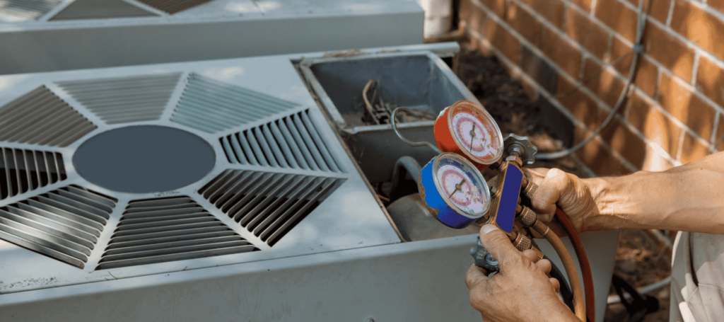 A technician holding pressure gauges while inspecting an HVAC outdoor unit