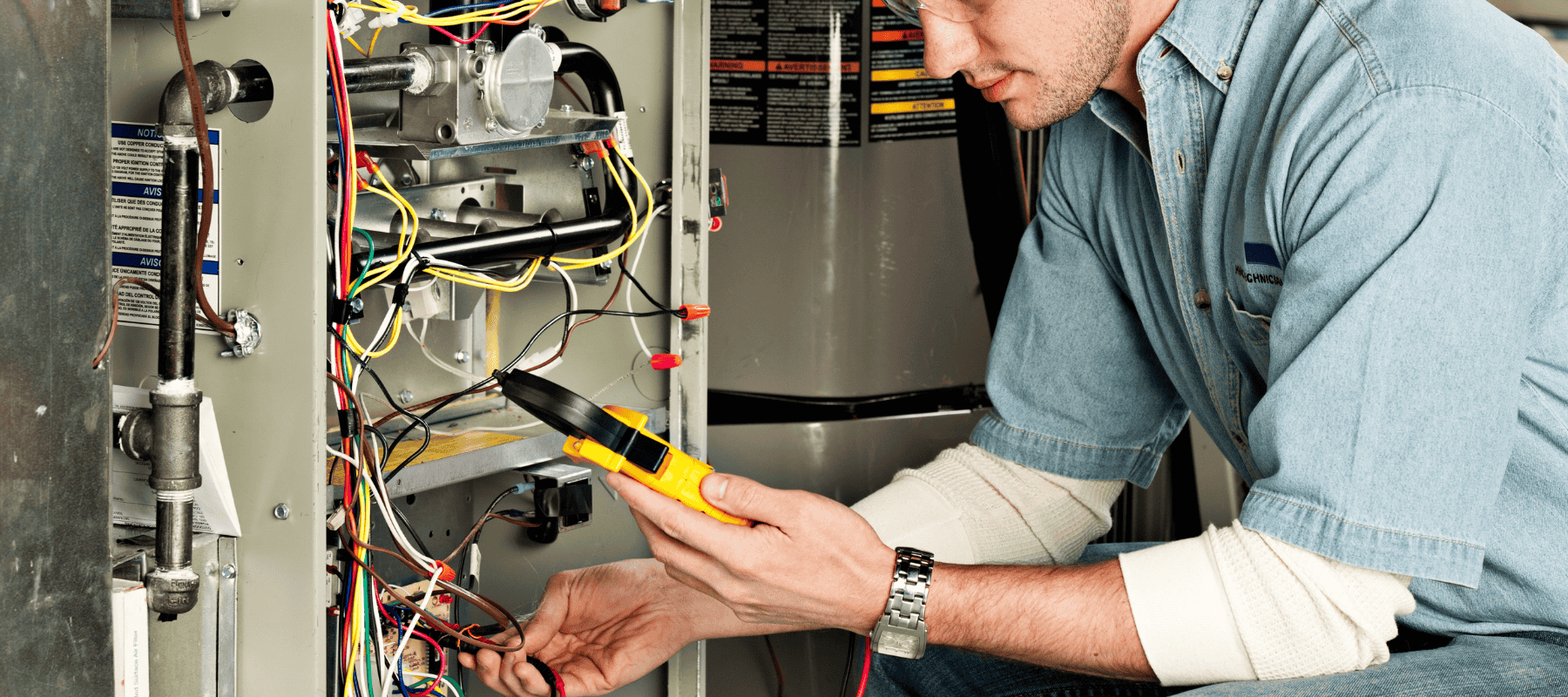A technician testing electrical connections inside a furnace system during a repair