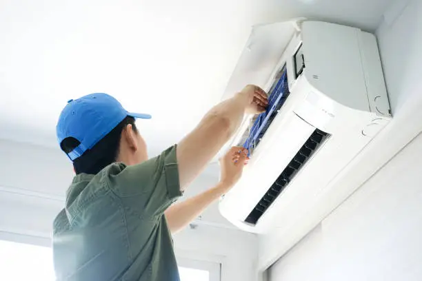 Technician checking airflow and thermostat settings in La Vernia family home